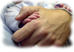 Mano de adulto cogiendo la manita de un beb&eacute;